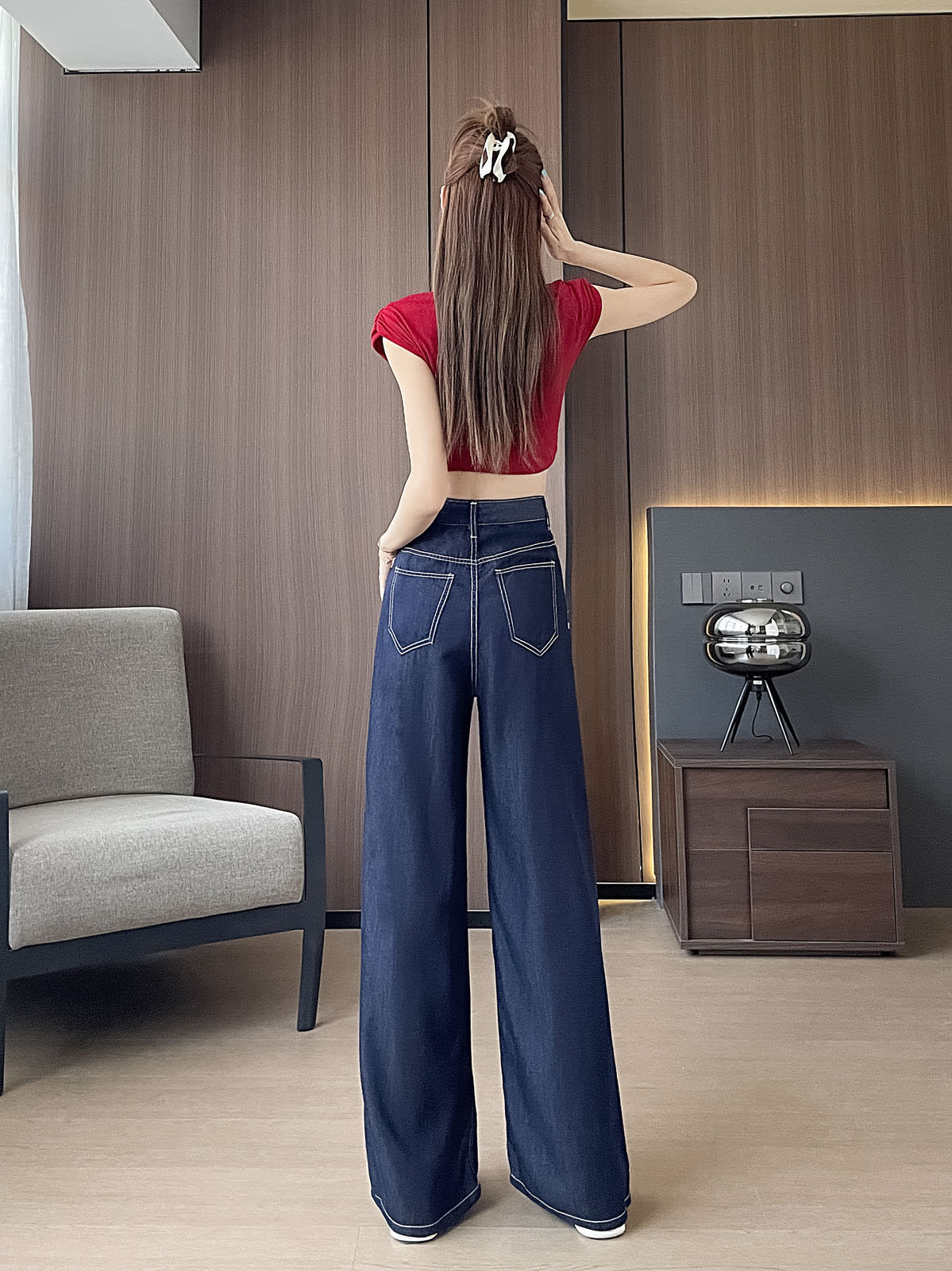 YEEYEEWang Wide-Leg Jeans in Denim Blue, Asian-fit cut, full-body back view standing, one hand raised to hair clip, double back patch pockets with contrast stitching.