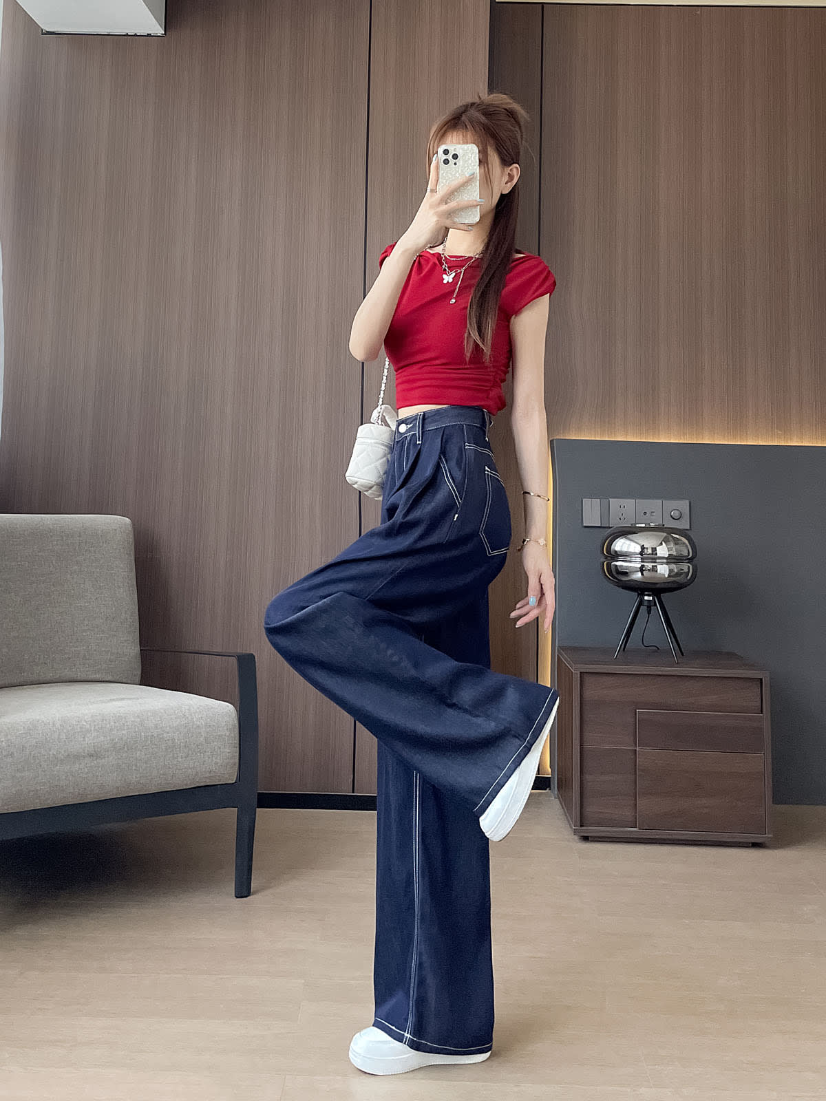 YEEYEEWang Wide-Leg Jeans in Denim Blue, Asian-fit cut, full-body side leg-kick pose holding phone at face, red crop top and white chain bag.
