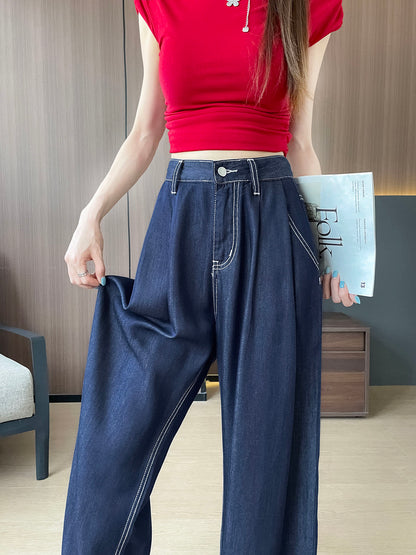 YEEYEEWang Wide-Leg Jeans in Denim Blue, Asian-fit cut, waist-down front view, one hand pinching the flowing fabric to show drape, the other holding a magazine.