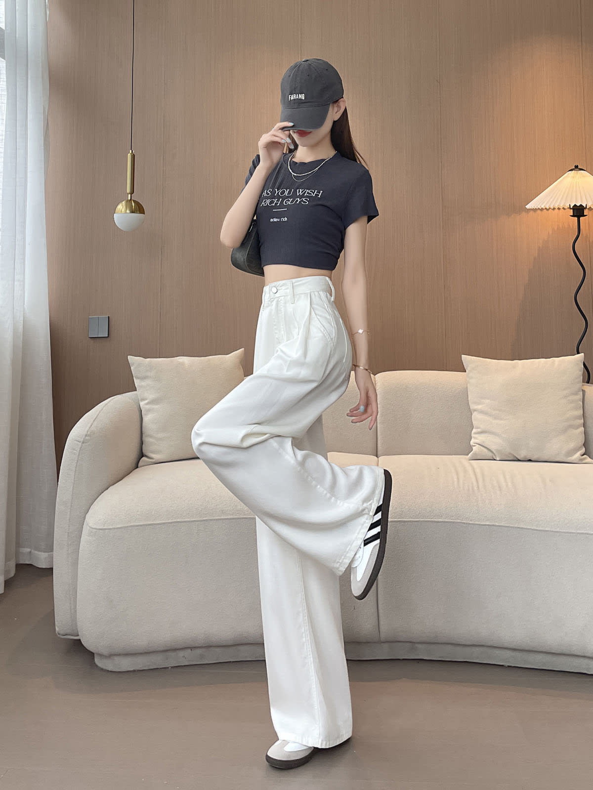 YEEYEEWang Wide-Leg Jeans in White, Asian-fit cut, full-body side leg-kick pose, one hand touching the cap brim, black shoulder bag.