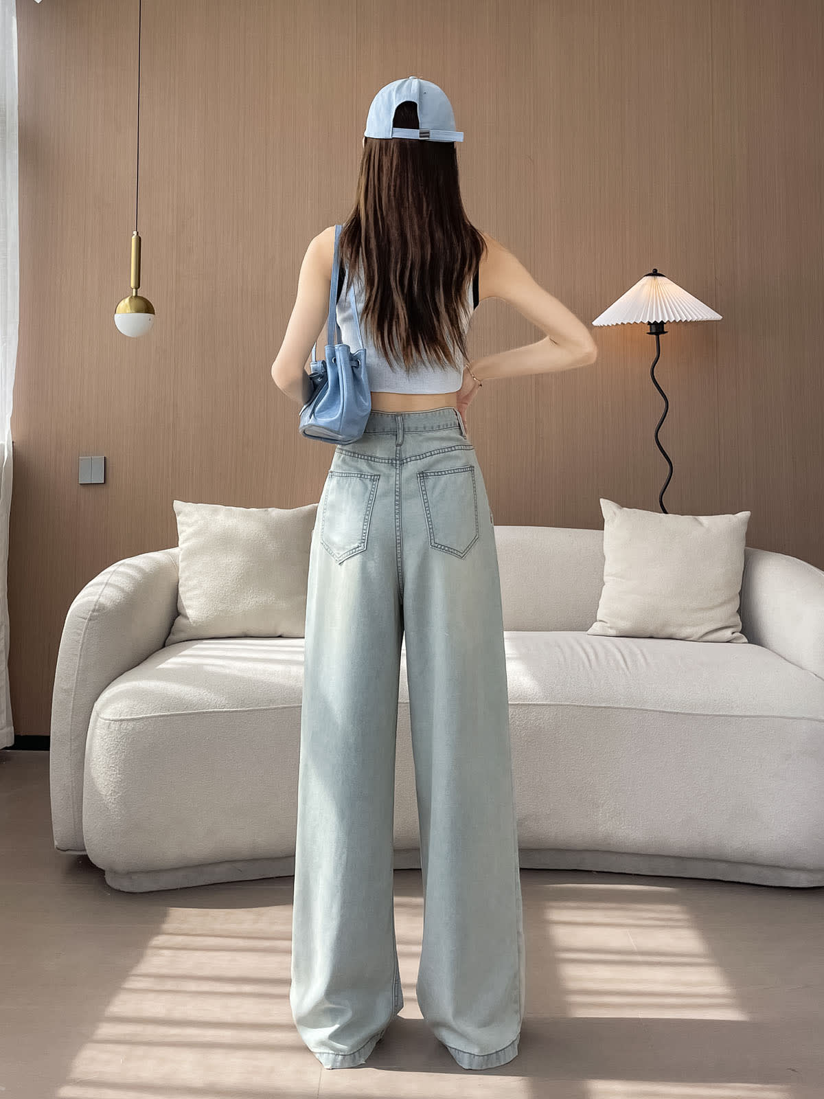 YEEYEEWang Wide-Leg Jeans in Light Blue, Asian-fit cut, full-body back view standing with back patch pockets, cap and blue shoulder bag.