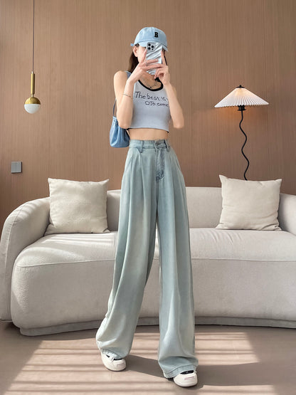 YEEYEEWang Wide-Leg Jeans in Light Blue, Asian-fit cut, full-body front pose with legs crossed holding phone at face, cap and blue bag styling.