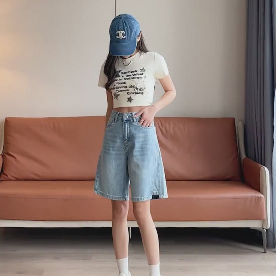 YEEYEEWang Denim Bermuda Shorts video in Blue: Asian model walks, lifts legs and turns to show high-waist wide-leg drape, frayed hems, daisy-embroidered back pockets in a cozy living room.