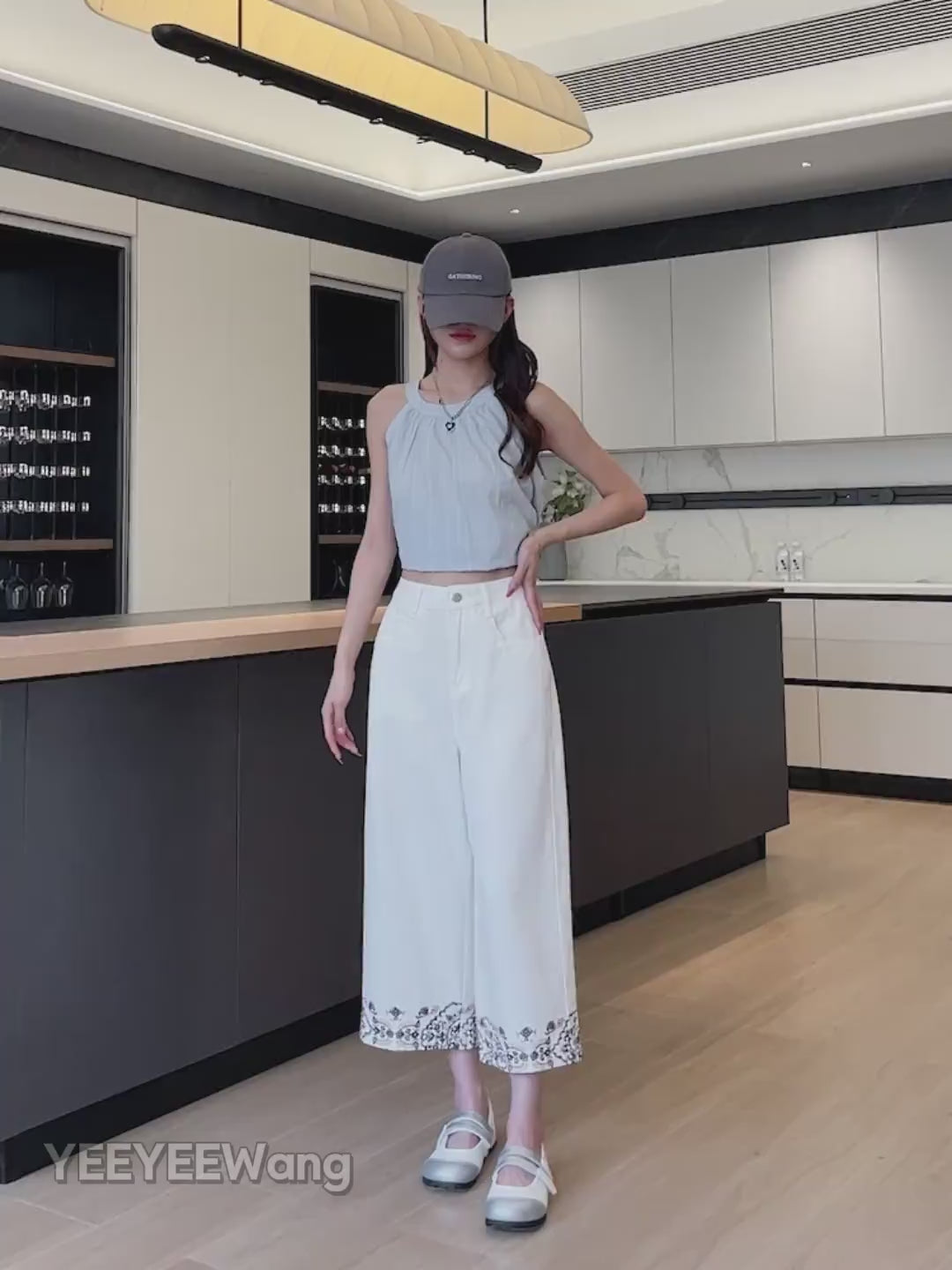 YEEYEEWang Wide-Leg Jeans video in Ivory: Asian model poses hand-on-hip and lifts leg in a modern kitchen, showing high-rise drape and floral hem embroidery.