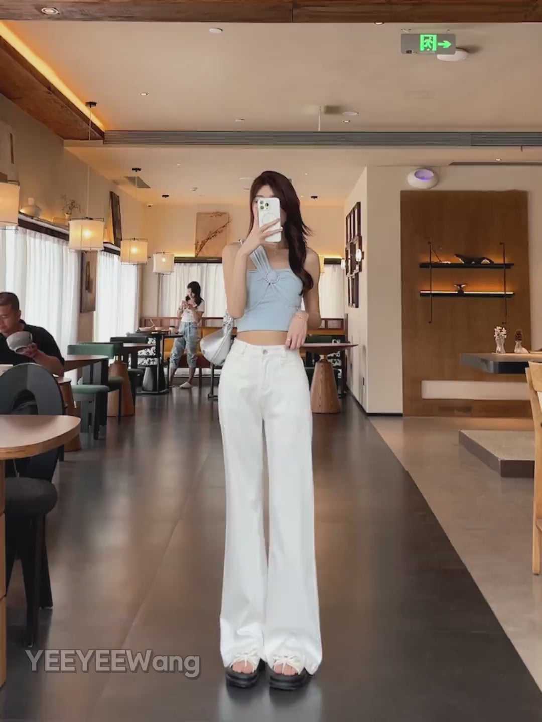 YEEYEEWang Flare jeans video: Asian model in White high-waist wide-leg denim turns and walks in a cafe, camera zooms in on draping hem and stacked cuffs.